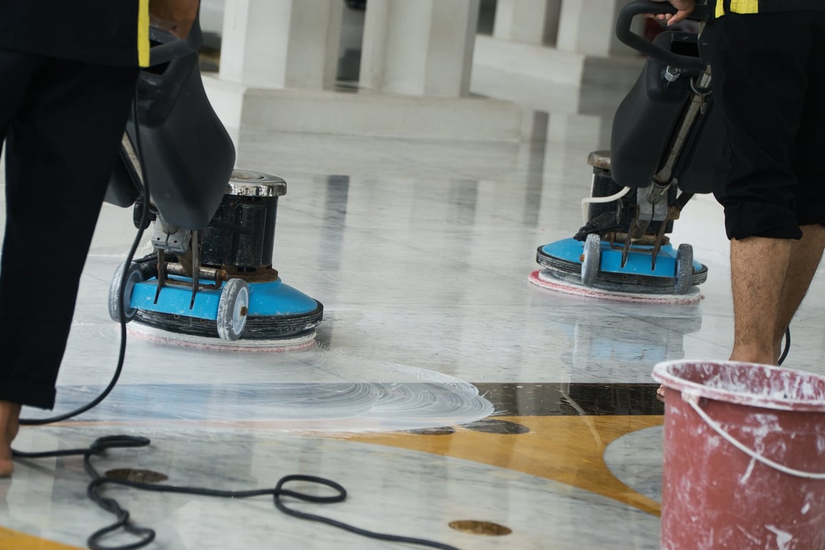 Professionals polishing a marble floor with buffing machines